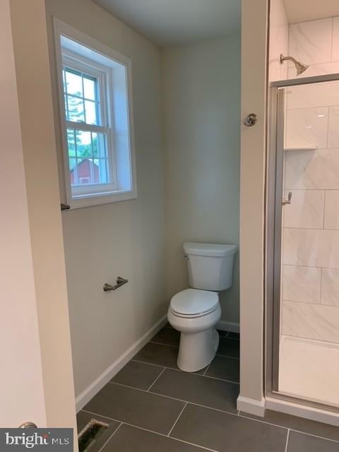 bathroom featuring tile patterned flooring, an enclosed shower, and toilet