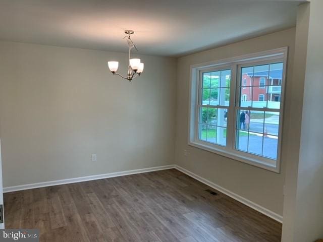 unfurnished room featuring dark hardwood / wood-style flooring and a notable chandelier