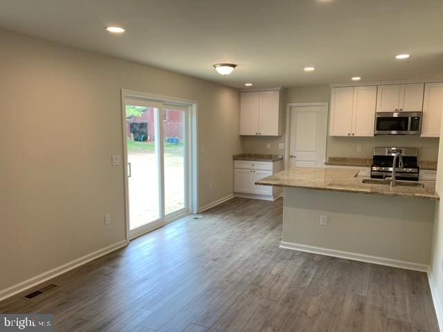 kitchen with sink, dark hardwood / wood-style floors, light stone counters, white cabinetry, and stainless steel appliances