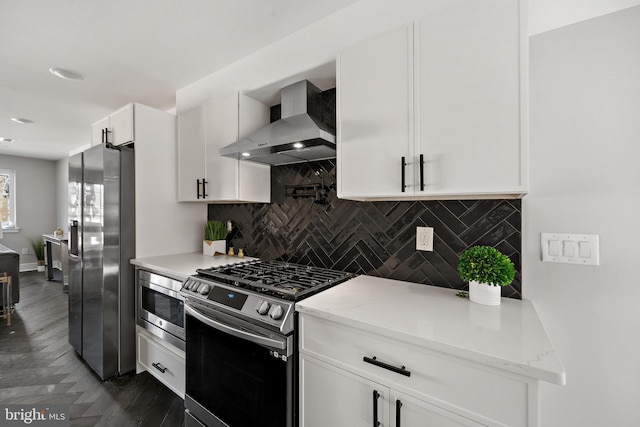 kitchen with decorative backsplash, appliances with stainless steel finishes, light stone counters, wall chimney exhaust hood, and white cabinetry