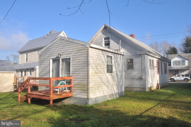 rear view of property featuring a deck and a lawn