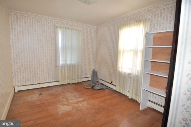 unfurnished room featuring baseboard heating and wood-type flooring