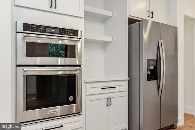 kitchen with white cabinets, stainless steel appliances, and light hardwood / wood-style flooring