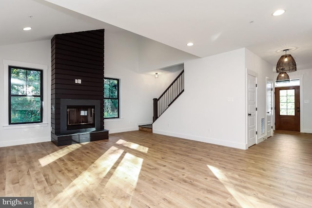 unfurnished living room with a multi sided fireplace, light hardwood / wood-style flooring, and plenty of natural light