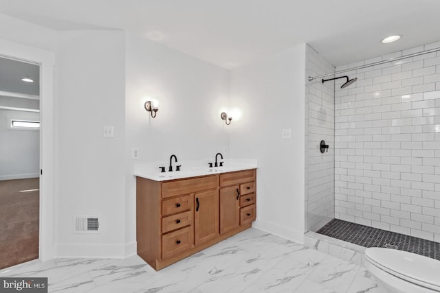 bathroom featuring vanity, toilet, and a tile shower