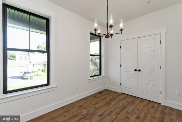 unfurnished dining area featuring dark hardwood / wood-style floors and a notable chandelier