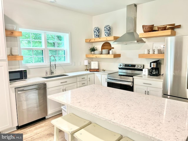 kitchen featuring white cabinets, sink, island range hood, light stone counters, and stainless steel appliances