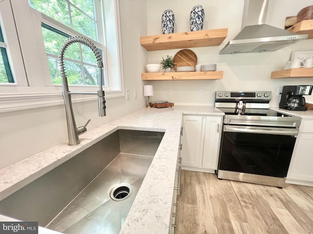 kitchen featuring exhaust hood, stainless steel electric stove, white cabinets, sink, and light stone countertops