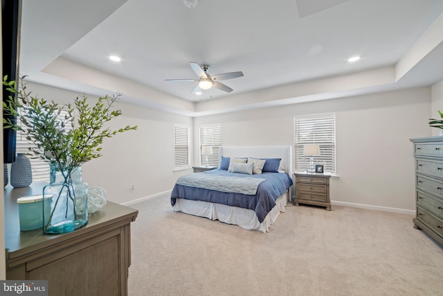 bedroom featuring a tray ceiling, multiple windows, and ceiling fan