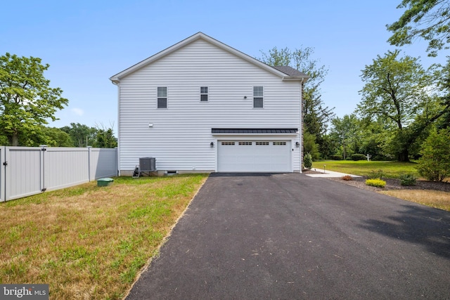 view of side of property featuring central AC, a yard, and a garage