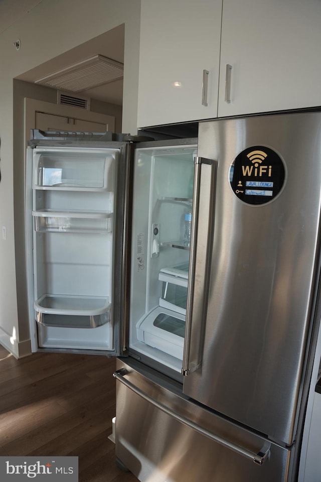 interior details featuring white cabinets, stainless steel fridge, and dark wood-type flooring