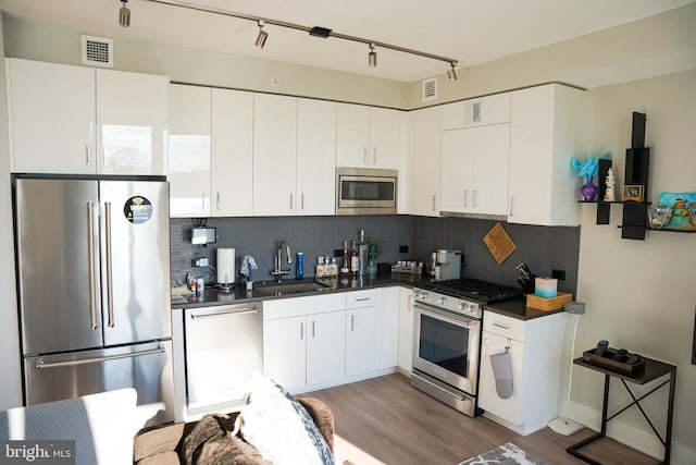 kitchen with appliances with stainless steel finishes, backsplash, white cabinetry, and sink