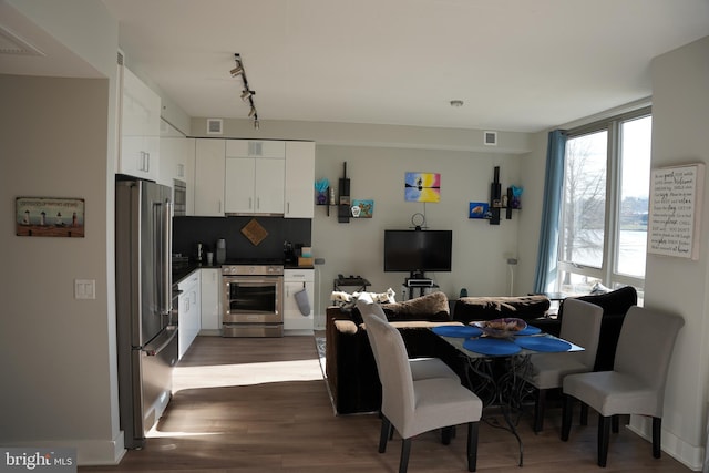 dining area with dark hardwood / wood-style flooring and rail lighting