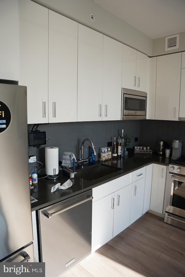 kitchen featuring backsplash, white cabinetry, and appliances with stainless steel finishes