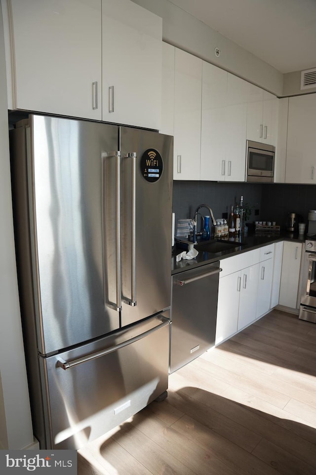 kitchen featuring sink, white cabinetry, stainless steel appliances, and tasteful backsplash