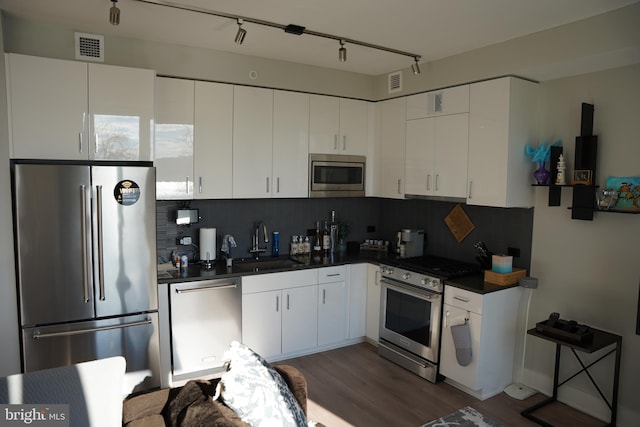 kitchen with white cabinetry, sink, rail lighting, stainless steel appliances, and tasteful backsplash