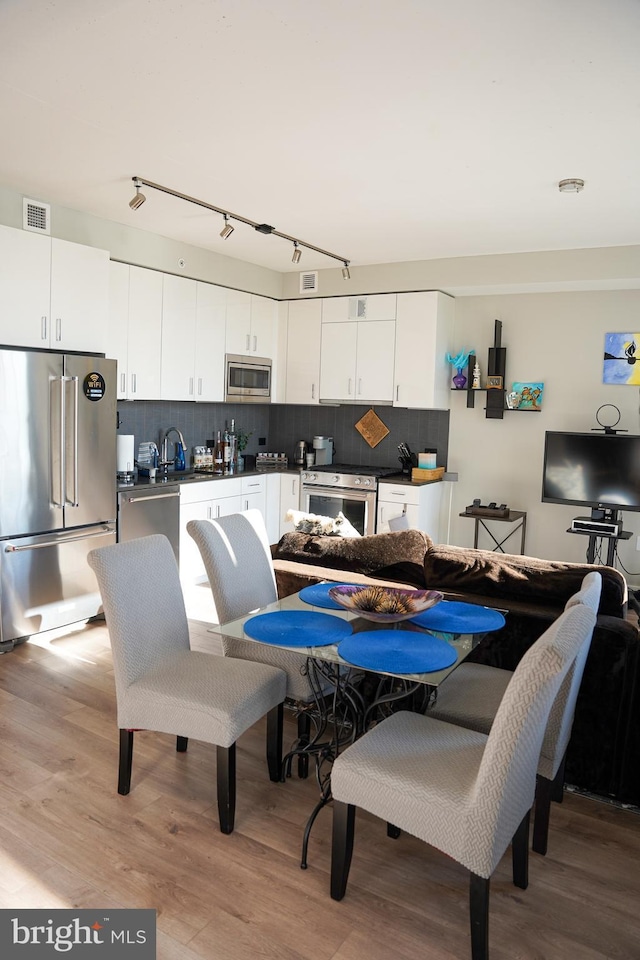 dining space featuring sink, light hardwood / wood-style floors, and track lighting