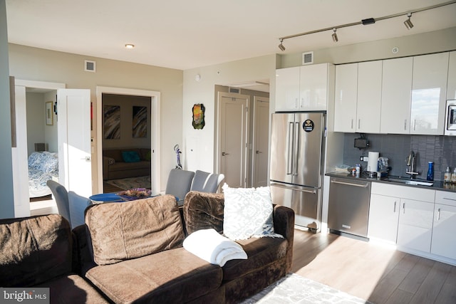 interior space with sink, rail lighting, and light hardwood / wood-style floors