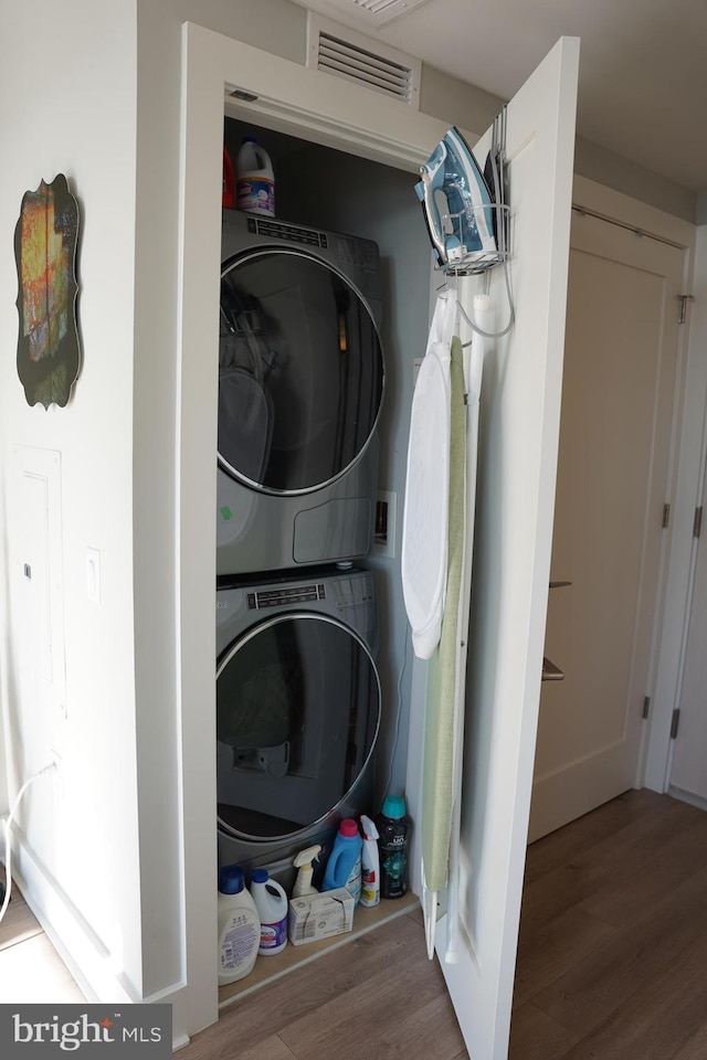 laundry area with hardwood / wood-style floors and stacked washer / drying machine