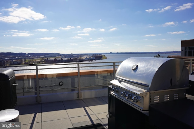 view of patio / terrace with a water view, a balcony, and grilling area