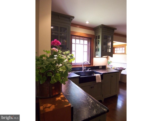 kitchen with kitchen peninsula, dark wood-type flooring, and sink