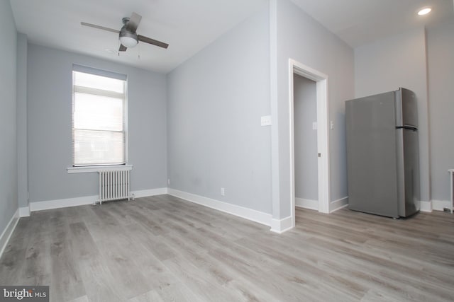 spare room with ceiling fan, radiator, and light hardwood / wood-style flooring