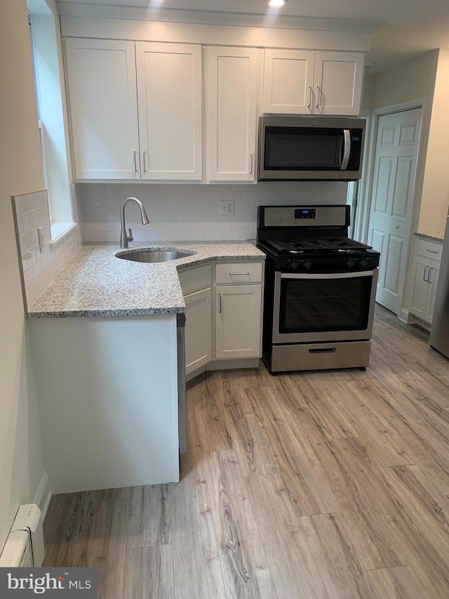 kitchen with white cabinets, appliances with stainless steel finishes, tasteful backsplash, and sink