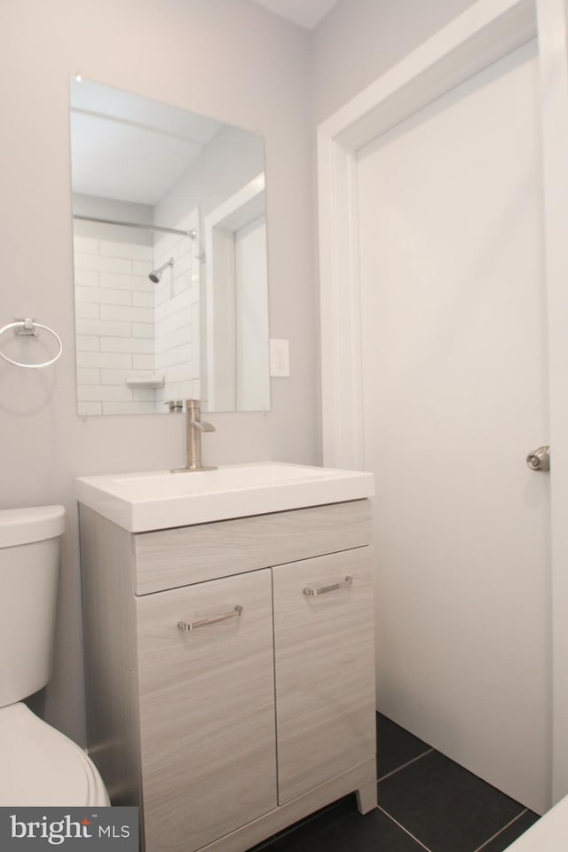 bathroom featuring tile patterned floors, walk in shower, vanity, and toilet