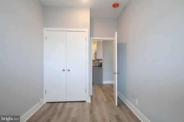 unfurnished bedroom with a closet and light hardwood / wood-style floors