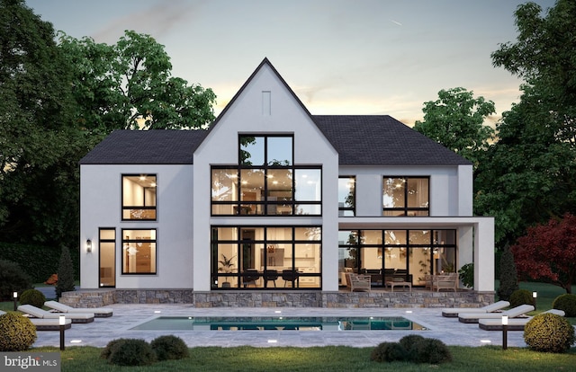 back house at dusk featuring a patio area and a balcony