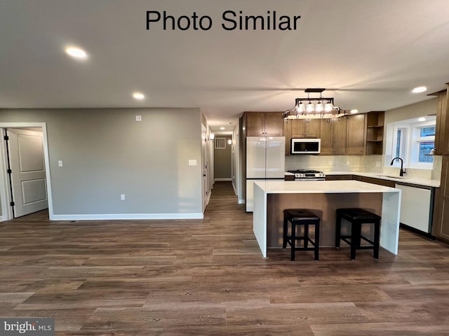 kitchen featuring pendant lighting, sink, a kitchen island, dark hardwood / wood-style flooring, and stainless steel appliances