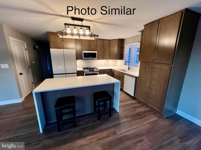 kitchen with appliances with stainless steel finishes, a kitchen island, hanging light fixtures, and sink