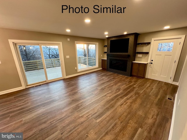 unfurnished living room featuring a large fireplace and dark wood-type flooring