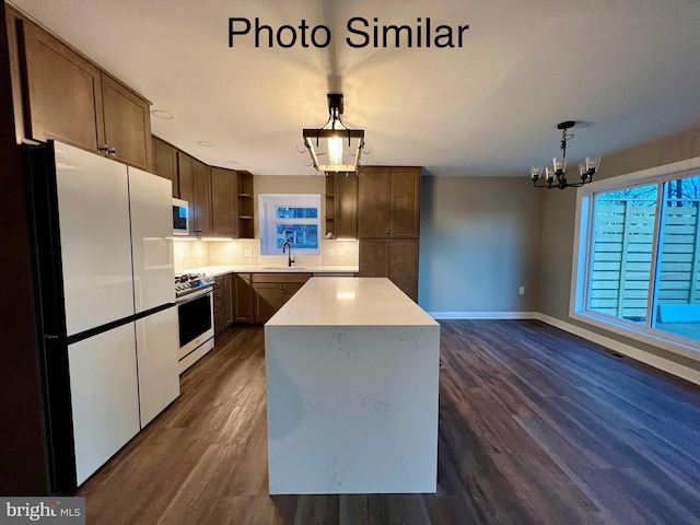 kitchen featuring a center island, white appliances, an inviting chandelier, sink, and hanging light fixtures