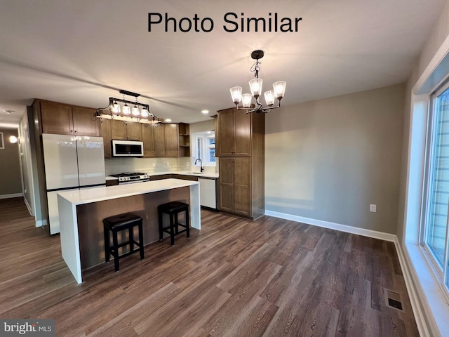 kitchen with hanging light fixtures, sink, appliances with stainless steel finishes, a kitchen island, and a chandelier