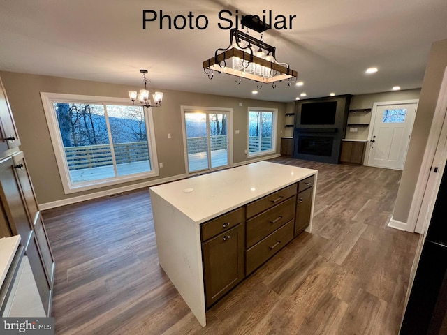 kitchen with pendant lighting, an inviting chandelier, a fireplace, dark hardwood / wood-style floors, and a kitchen island