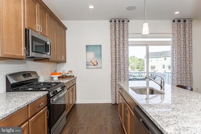 kitchen with sink, hanging light fixtures, dark hardwood / wood-style floors, light stone countertops, and stainless steel appliances