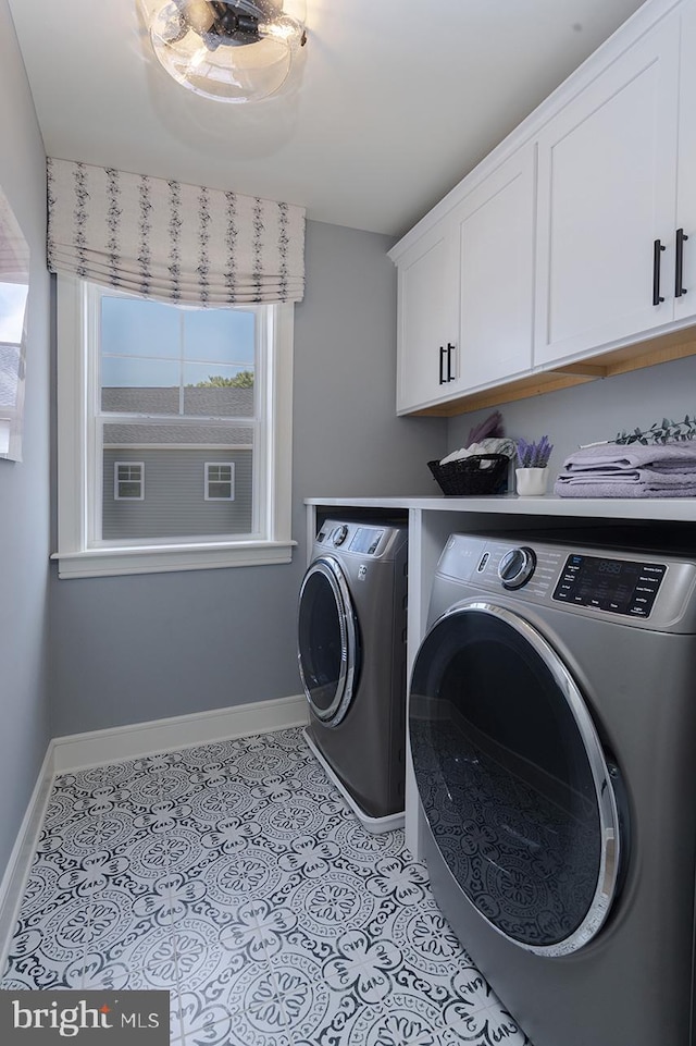 clothes washing area featuring cabinets and washing machine and clothes dryer