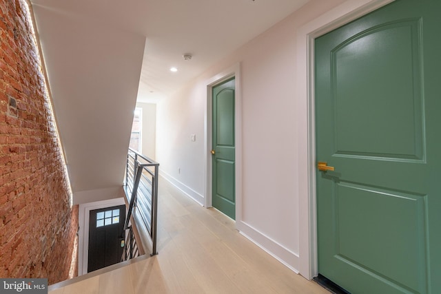 corridor featuring light hardwood / wood-style floors and brick wall