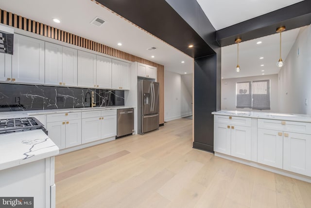 kitchen featuring pendant lighting, white cabinetry, backsplash, and appliances with stainless steel finishes