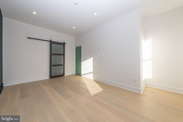 empty room featuring a barn door and light wood-type flooring