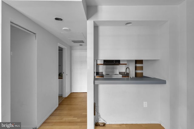 kitchen featuring sink, light wood-type flooring, and white stove