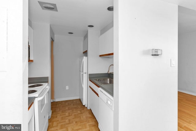 kitchen with light parquet floors, sink, white appliances, and white cabinets