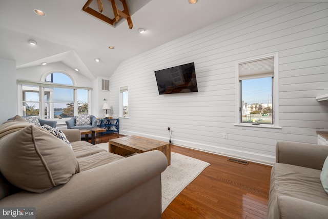 living room featuring wood walls, wood-type flooring, and vaulted ceiling