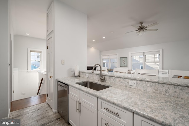 kitchen featuring white cabinets, dishwasher, light stone counters, and sink