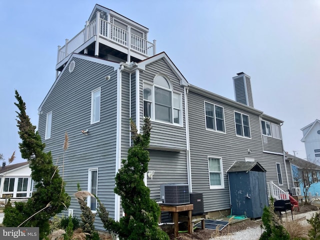 rear view of house featuring central air condition unit and a balcony