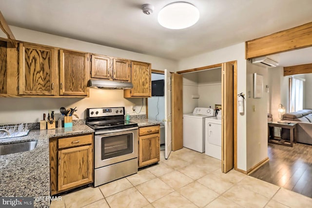 kitchen with sink, washing machine and dryer, an AC wall unit, stone countertops, and stainless steel range with electric stovetop