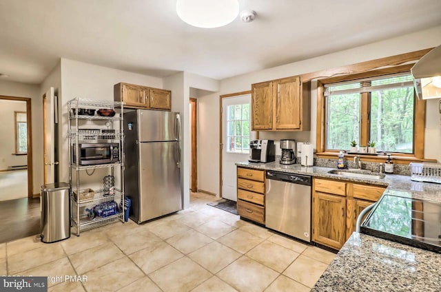 kitchen featuring a healthy amount of sunlight, light stone countertops, sink, and appliances with stainless steel finishes