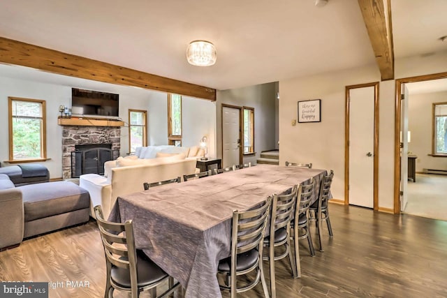 dining space featuring beam ceiling, wood-type flooring, and a fireplace