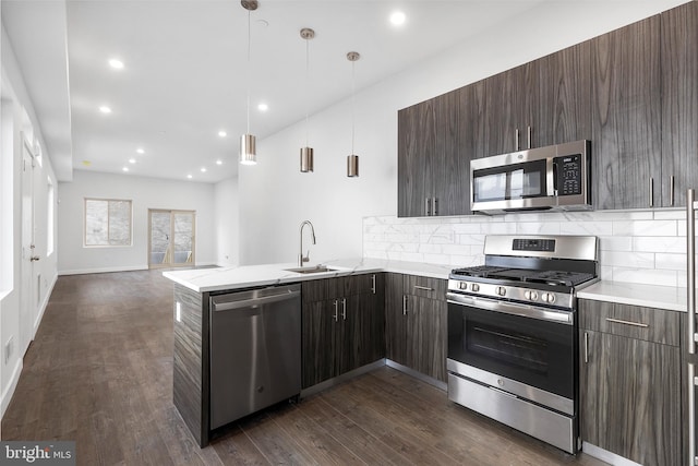 kitchen featuring dark hardwood / wood-style floors, stainless steel appliances, decorative light fixtures, and backsplash